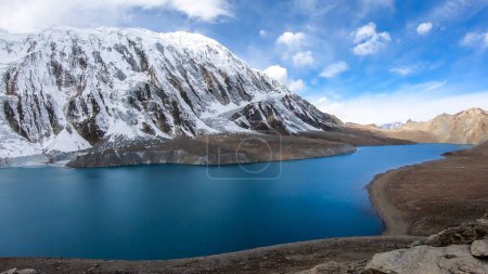 Foto de Una vista panorámica del lago Tilicho de color turquesa en Himalaya, región de Manang en Nepal. El lago de mayor altitud del mundo (4949m). Montañas cubiertas de nieve alrededor. Superficie tranquila del lago. Serenidad - Imagen libre de derechos