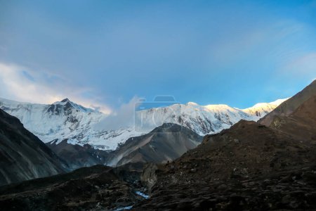 Téléchargez les photos : Vue rapprochée sur les sommets enneigés de l'Himalaya le long du circuit de l'Annapurna au Népal. Pentes stériles et abruptes. Les montagnes sont partiellement couvertes de nuages. Exploration et découverte de nouveaux lieux - en image libre de droit
