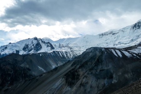 Téléchargez les photos : Le temps orageux dans la neige a couvert les sommets himalayens le long du circuit de l'Annapurna au Népal. Pentes stériles et abruptes. Les montagnes sont partiellement couvertes de nuages. Exploration et découverte de nouveaux lieux. Froid - en image libre de droit