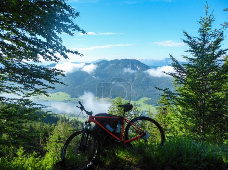 Téléchargez les photos : A mountain bike on a ride with the view on the Weissensee lake in Austria. The view from above. The lake is surrounded by the Alps. Exercising on the free air. Many mountain chains. Sunny day - en image libre de droit