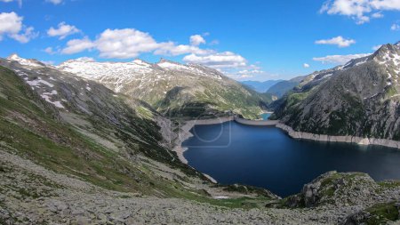 Photo for A panoramic view on an artificial, dam lake stretching over a vast territory around Alps in Austria. Lake is shining with navy blue color. In the back there are a few glaciers. Controlling the nature - Royalty Free Image