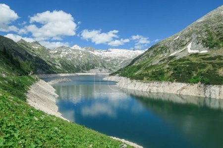 Photo for Dam in Austrian Alps. The artificial lake stretches over a vast territory, shining with navy blue color. The dam is surrounded by high mountains. In the back there is a glacier. Controlling the nature - Royalty Free Image