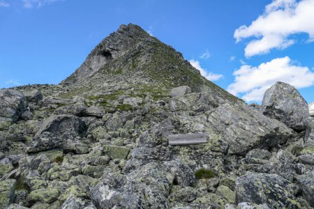 Photo for A view on Arlhoehe peak from below in Maltal region in Austrian Alps. The peak is surrounded by lose stones and boulders. Difficult climbing. There is a wooden bench on the side. Hiking season - Royalty Free Image
