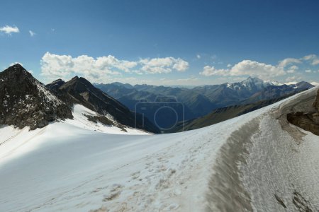 Photo for A footprints on the snow, lying on a glacier under Hohe Sonnblick in Austrian Alps. The footprints lead in one direction. Many high mountain chains in the nearby. Clear and sunny day. Mountainerring - Royalty Free Image