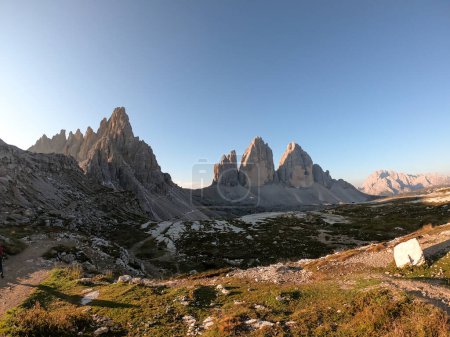 Téléchargez les photos : A panoramic capture of the Tre Cime di Lavaredo (Drei Zinnen) and surrounding mountains in Italian Dolomites. The mountains are surrounded by thick clouds. Early morning in the mountains. Daybreak - en image libre de droit