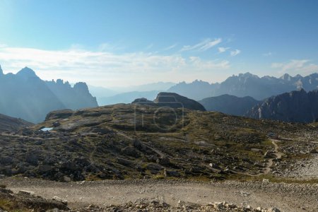 Foto de Una vista sobre un vasto valle en los Dolomitas italianos. El valle está rodeado de altas montañas de cada lado. Sol fuerte, temprano en la mañana. Hay unas cuantas nubes arriba. Lugar remoto y aislado. Remedio - Imagen libre de derechos