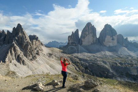 Téléchargez les photos : A woman in hiking outfit standing with her arms wide open and enjoying the view on the famous Tre Cime di Lavaredo (Drei Zinnen), mountains in Italian Dolomites. Desolated and raw landscape. Freedom - en image libre de droit