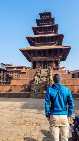 Foto de Un hombre con gorro parado frente a un templo en Bhaktapur, templo Nyatapola. El templo hindú tiene cinco pisos. Descubriendo nuevas culturas. Un lugar de culto religioso e histórico. La espiritualidad - Imagen libre de derechos