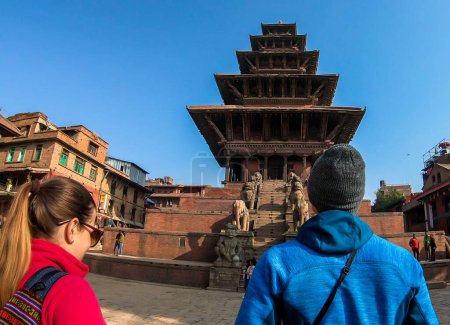 Foto de Una pareja caminando por la plaza Taumadhi hacia el Templo Nyatapola en Bhaktapur, Nepal. El templo hindú tiene cinco pisos. Descubriendo nuevas culturas. Un lugar de culto religioso e histórico. La espiritualidad - Imagen libre de derechos