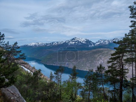 Photo for Akrafjorden is a fjord in Hordaland county, Norway. Seen from the middle hill level. Slopes are overgrown with green trees and bushes, in the back higher mountains are covered with snow. - Royalty Free Image