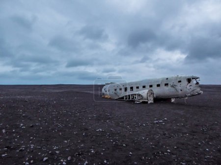 Foto de Solheimasandur Plane Wreck situado en una playa de arena negra en Islandia. Pocos guijarros visibles en la arena negra. Atmósfera oscura y solemne. El naufragio del avión ya no tiene alas ni cola. - Imagen libre de derechos