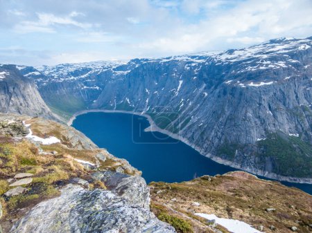 Téléchargez les photos : A beautiful view from the above on Ringedalsvatnet lake, Norway. Lake is located in between tall mountains. Slopes of the mountains are partially covered with snow. The water of the lake is navy blue. - en image libre de droit