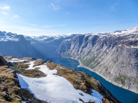 Téléchargez les photos : A beautiful view from the above on Ringedalsvatnet lake, Norway. Lake is located in between tall mountains. Slopes of the mountains are partially covered with snow. The water of the lake is navy blue. - en image libre de droit