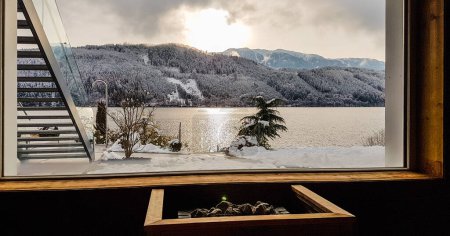 Photo for Alpine sauna with the view on the lake and the mountains. Under the window there is a furnace, warming the stones. Mountains covered with snow. Relaxation and chill in winter wonderland. - Royalty Free Image