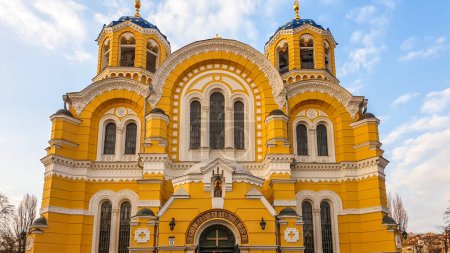 Téléchargez les photos : Un gros plan sur l'entrée principale de la cathédrale St Volodymyr à Kiev, en Ukraine. La cathédrale a des murs jaunes et un toit bleu. Ciel nuageux autour du bâtiment. - en image libre de droit