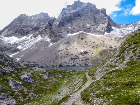 Téléchargez les photos : Vallée avec un petit lac au milieu, situé entre la chaîne de montagnes pointues et pierreuses de Dolomites de Lienz, Autriche. Les pentes sont stériles, avec peu d'herbe dessus. Alpinisme dangereux. - en image libre de droit