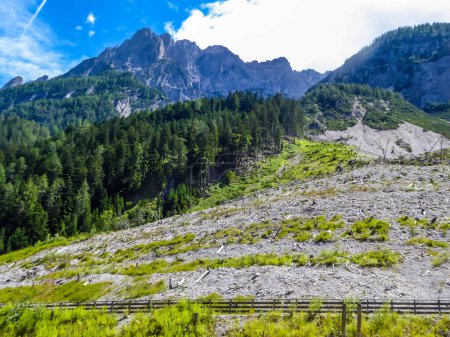 Téléchargez les photos : Une vue sur la chaîne de montagnes pierreuses et escarpées de Lienz Dolomites, Autriche. Les pentes sont envahies par des arbres et des parties inférieures par des buissons Une clôture longeant la montagne. Alpinisme dangereux. - en image libre de droit