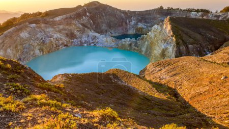 Foto de Salida del sol sobre los lagos del cráter volcánico Kelimutu en Moni, Flores, Indonesia. Skyline está lleno de naranja. Color turquesa del lago. La hora dorada colorea el entorno. Belleza de la naturaleza - Imagen libre de derechos