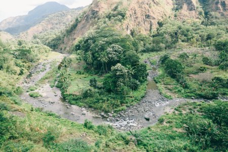 Foto de Un hermoso valle en la isla de Flores en Indonesia. Un río mágico fluye a través de una selva salvaje que aparece en colores verdes brillantes. Su día soleado, buenas vibraciones. - Imagen libre de derechos
