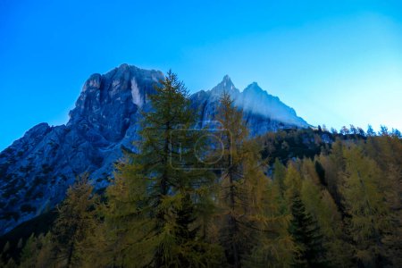 Photo for A panoramic view on Lienz Dolomites, Austria, bathing in the morning sun. The sun beams are coming into the valley through high mountain peaks, reaching the lower located forest. New day begins - Royalty Free Image