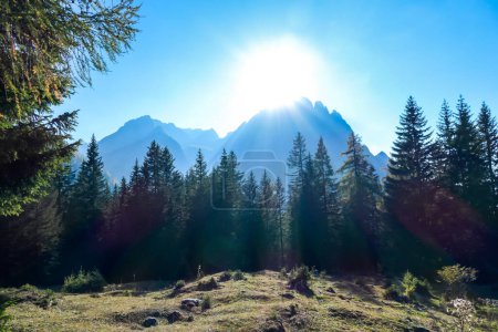 Téléchargez les photos : Vue panoramique sur les Dolomites de Lienz, Autriche, baignade au soleil du matin. Les rayons du soleil pénètrent dans la vallée par de hauts sommets montagneux, atteignant la forêt située en aval. Le nouveau jour commence - en image libre de droit