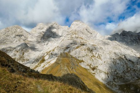 Photo for Golden colored mountains range at Austrian-Italian border. The autumn vibes in Alps, nature getting ready for hibernation. Sharp rocky Alpine peaks. Serenity and peace. Clouds breaching high mountains - Royalty Free Image