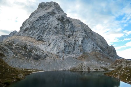 Photo for Panoramic shot of a soft reflection of an Alpine mountain in Wolayer Lake, Austria. Completely still surface of the lake. Mountain is surrounded by morning haze. Peace of mind, calmness. - Royalty Free Image