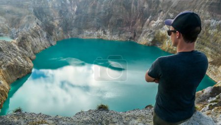 Foto de Hombre parado en el borde del volcán y observando los lagos del cráter volcánico Kelimutu en Moni, Flores, Indonesia. El hombre se involucra con la vida y tiene el sentimiento de libertad - Imagen libre de derechos