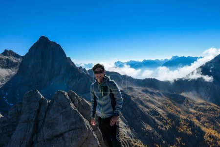 Téléchargez les photos : Un homme debout sur le sommet de Grosse Gamswiesenspitze à Lienz Dolomites, Autriche. Des pentes vives et dangereuses. Montagnes alpines massives. Un vagabond solitaire. Il est heureux et fier de sa réussite. Liberté - en image libre de droit