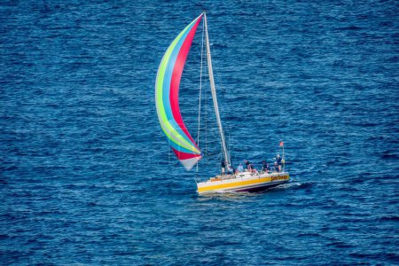 Téléchargez les photos : Puerto Galera, Philippines - 30 mars 2013. Un yacht naviguant sous le vent dans une régate locale, avec son spinnaker coloré volant et l'équipage sur le pont. - en image libre de droit