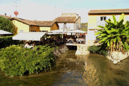 Téléchargez les photos : Vue depuis Borghetto sur la rivière Mincio avec des touristes déjeunant le long de la rivière. 22 octobre 2023 Borghetto, Vénétie, Italie - en image libre de droit