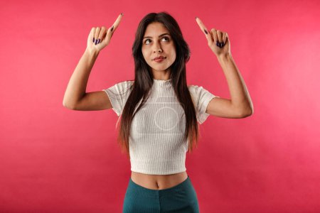 Foto de Young beautiful woman wearing ribbed crop isolated over red background look pointing up upset, feel jealous, regret, missing good opportunity, staring unhappy top advertisement. Unhappy and depressed. - Imagen libre de derechos
