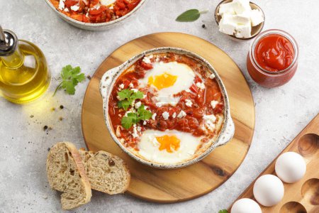 Photo for Traditional north african dish shakshouka made of eggs poached in a sauce of tomatoes, olive oil, bell peppers, onion and garlic, spiced with cumin, paprika and cayenne pepper - Royalty Free Image