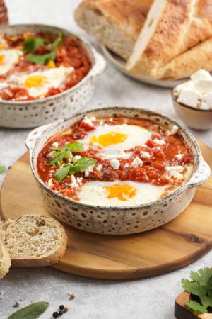 Téléchargez les photos : Plat traditionnel nord-africain shakshouka à base d'œufs pochés dans une sauce de tomates, huile d'olive, poivrons, oignon et ail, épicé au cumin, paprika et poivre de Cayenne - en image libre de droit