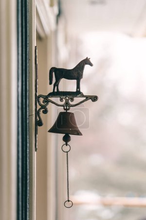 Téléchargez les photos : Cloche de cheval accrochée à la fenêtre. Style vintage. Concentration sélective. - en image libre de droit