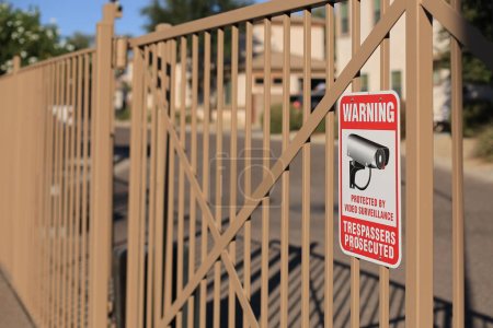 Téléchargez les photos : Des intrus ont poursuivi un panneau d'avertissement placé sur les barreaux d'une clôture métallique dans une collectivité résidentielle fermée à logements sociaux. - en image libre de droit