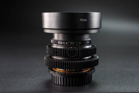 Pila de lente de cámara profesional, enfocada en ajustes de apertura, etiqueta de 72mm en superficie metálica lisa, equipo fotográfico resaltado por iluminación suave.