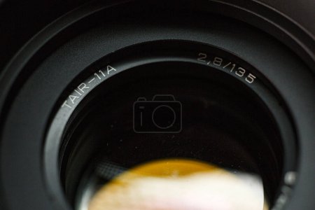 Foto de Vista detallada del grabado del objetivo de la cámara TAIR-11A, con longitud focal y valor de apertura, instrumento de precisión para la fotografía, sobre un fondo oscuro borroso. - Imagen libre de derechos
