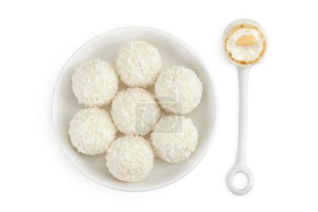 round candy raffaello with coconut flakes and nut in ceramic bowl isolated on white background. Top view. Flat lay