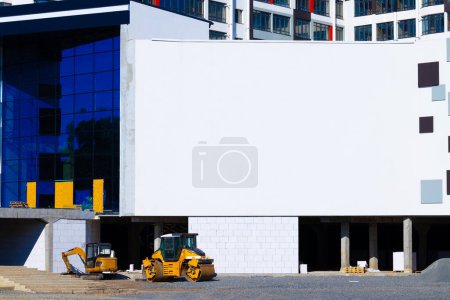 advertisement wall empty copy space template in modern building construction area architecture exterior yard environment with equipment, material and transport sidewalk rink bulldozer object