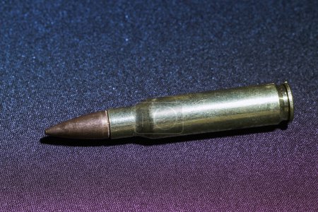 Photo for Caliber 5,56 bullet for rifle gun macro close up photography in textured dark carpet background with glamour blue and purple neon color gradient - Royalty Free Image
