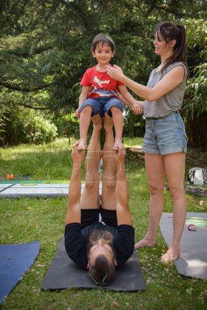 Téléchargez les photos : Jeune garçon faire un exercice d'équilibre avec ses entraîneurs dans le jardin - en image libre de droit