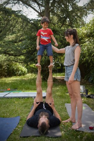 Téléchargez les photos : Jeune garçon faire un exercice d'équilibre avec ses entraîneurs dans le jardin - en image libre de droit