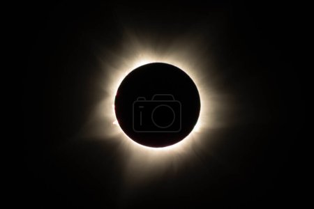 Photo for View of the moon moving in front of the sun, plunging the sky into darkness as only a few sunrays escape. Ningaloo Exmouth 2023 TSE, lasting for only a minute. Red prominences of the sun visible - Royalty Free Image