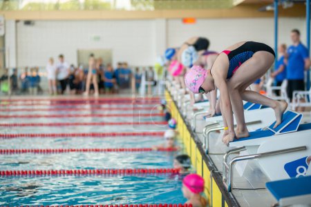 Foto de Nadadora chica empezar desde la mesa de partida en la piscina - Imagen libre de derechos