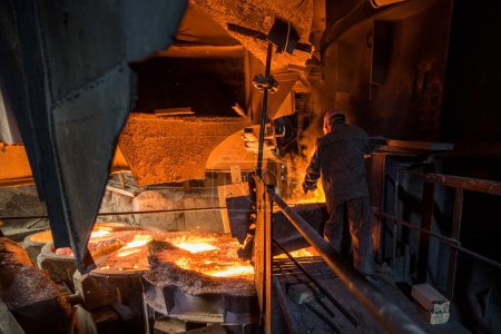 Stahlarbeiter bei der Arbeit in der Nähe von Lichtbogenofen und Gießen von flüssigem Metall