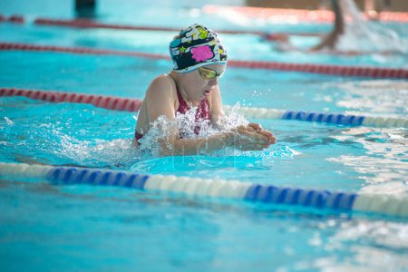 Foto de Nadador niño nada al estilo de natación de pecho en la piscina - Imagen libre de derechos