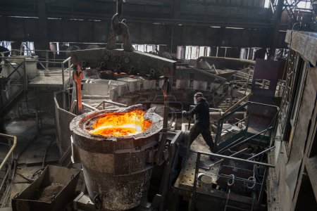Foto de Trabajador siderúrgico en el trabajo cerca de los tanques con metal caliente - Imagen libre de derechos