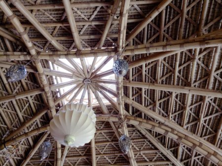 Bamboo ceiling and roofing details close up shot. Tropical architecture interior design showing complicated handcrafted structure. Hanging lamp on the ceiling. Low angle perspective.
