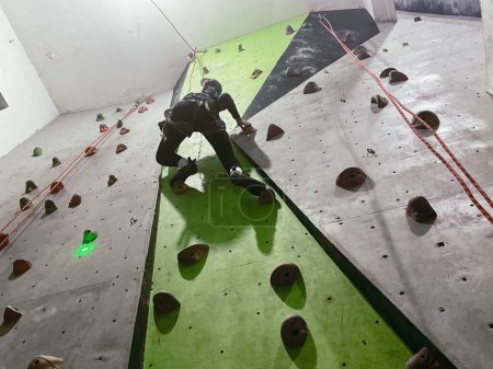 Young woman doing indoor rock climbing, low angle shot
